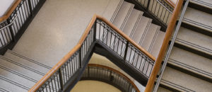 beige terrazzo staircase with two black abrasive strips and a wooden railing