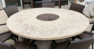 white, yellow, and red outdoor terrazzo table with black chairs surrounding it.