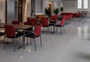 white terrazzo floor with metal divider strips, red chairs, and tables