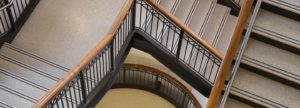 beige precast terrazzo staircase with two black abrasives strips and a wooden railing
