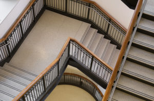 beige terrazzo staircase with wooden railing and two black abrasive strips