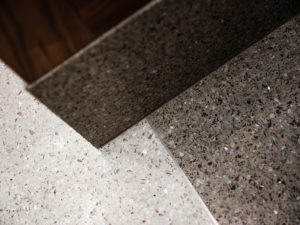 white and brown terrazzo floor with a metal divider strip and terrazzo straight base